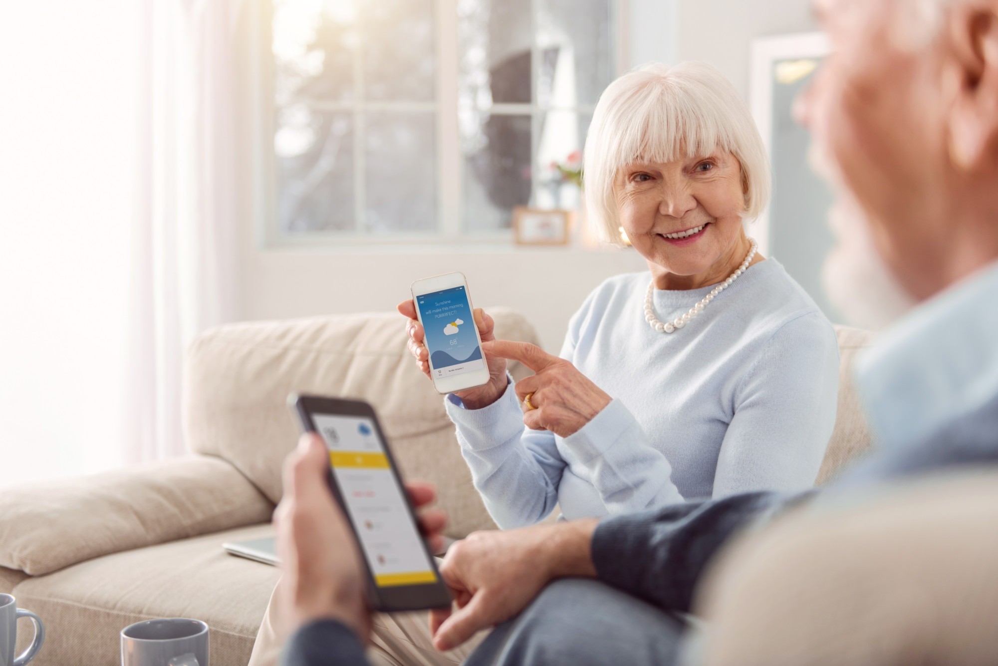 Upbeat senior woman showing weather app to her husband
